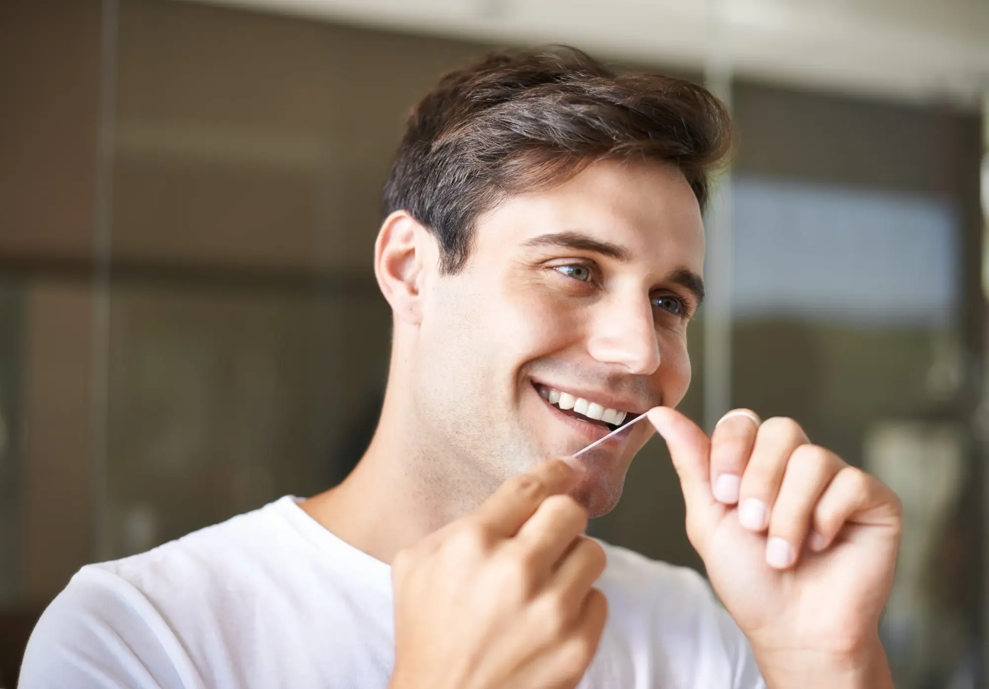 Man flossing his teeth at home